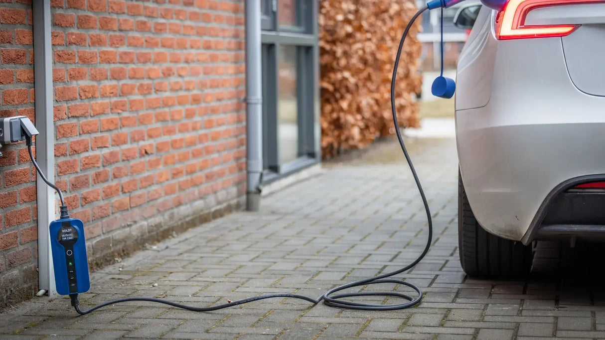 Een zilverkleurige elektrische auto staat geparkeerd op een oprit en wordt opgeladen met de 🇳🇱 Type 2 Schuko 230V Mobiele laadkabel | thuislader | Regelbaar 3,7kW | 3 jaar garantie. Dit laat zien hoe handig thuis EV opladen is met dit Nederlandse product.
