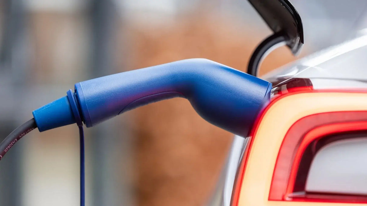 Een close-up van de 🇳🇱 Type 2 Schuko 230V Mobiele laadkabel (regelbaar 3,7kW, thuislader) aangesloten op een zilveren auto met verlicht achterlicht. Inclusief 3 jaar garantie.