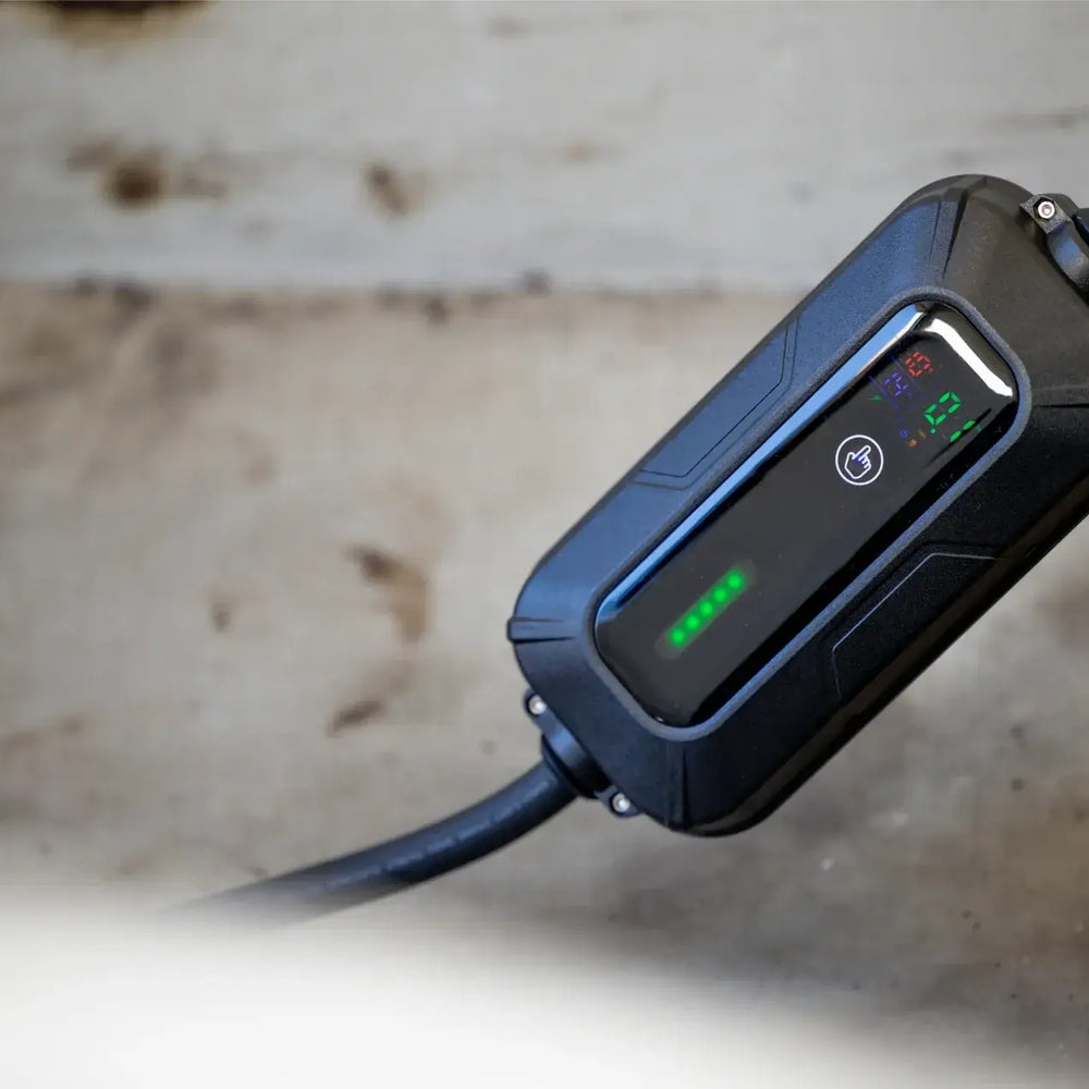 Een close-up van de 🇳🇱 VOLDT Booster Master Travelset - 22kW 3-Fase Professionele Laadoplossing connector met groene LED's, rustend op beton - ideaal voor snel mobiel opladen van EV's onderweg.