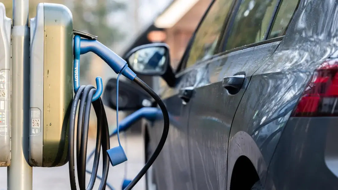 Een close-up van een elektrische auto die buiten wordt opgeladen met een 🇳🇱 VOLDT Type 2 Mode 3 16A 11kW Laadkabel, bekend om kwaliteit en IP67-bescherming, aangesloten op het voertuig op een heldere dag.