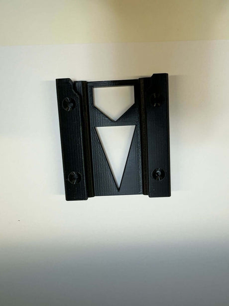 Een zwarte kunststof Accuhouder voor Hilti (per 2 stuks) met twee zijschroeven en een centrale uitsparing - een omgekeerde driehoek onder een kleinere rechtopstaande driehoek - afgebeeld op een wit vlak.