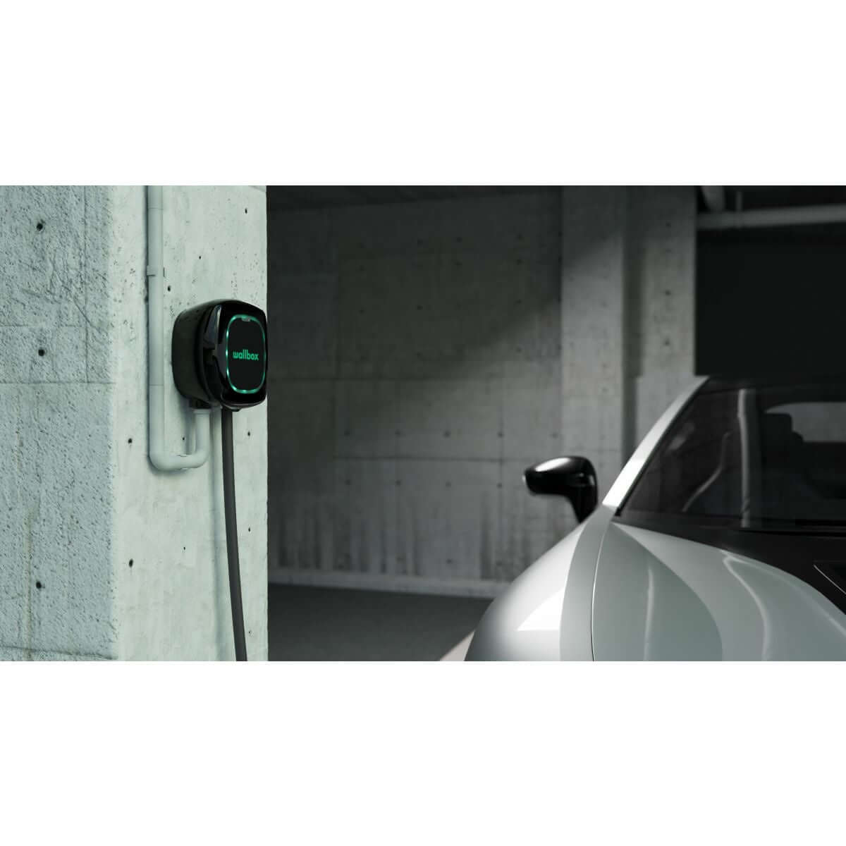 Een strakke elektrische auto staat geparkeerd in een moderne garage naast een Voordeelset Laadstation Wallbox Pulsar Plus (3,7kW-22kW) met type 2 vaste kabel (5 & 7 meter), het display licht zachtjes op.