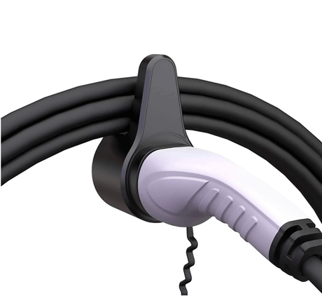 Een witte en zwarte EV-laadstekker is gemonteerd op een muurbeugel, met de lange zwarte kabel netjes opgerold rond de Kabelhouder type 2 laadkabel EV.
