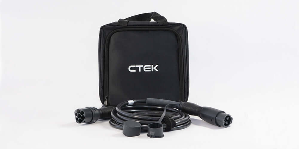 Een zwarte CTEK-draagtas zit achter een opgerolde CTEK Laadkabel type 2 naar type 1 SAE J1772 1-fase 32A met twee zwarte connectoren en beschermkappen, alles tegen een witte achtergrond.