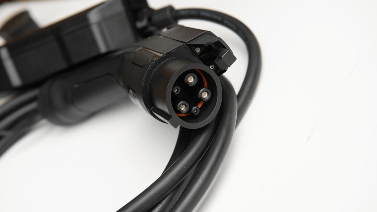 Een close-up van een Thuislader stopcontact type 1 1-fase 6A-16A 1,3kW-3,6kW voor elektrische auto, met een zwarte Type 1 laadstekker met spiraalkabel op een wit oppervlak voor flexibel thuis EV laden.