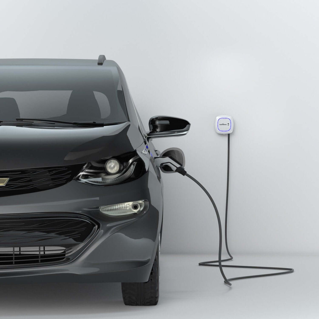 Een zwarte elektrische auto staat geparkeerd en wordt opgeladen via een Voordeelset Laadstation Wallbox Pulsar Plus 3,7kW tot 22kW met een type 2 vaste kabel, aangesloten aan de voorkant in een minimale, lichtgrijze binnenruimte.