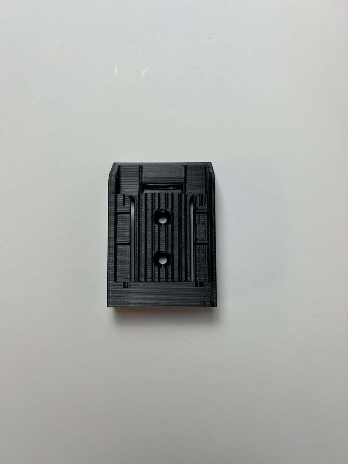 Een zwarte rechthoekige kunststof accuhouder voor DeWalt DCB180, DCB181 en DCB181-XJ (per 6 stuks) met groeven, opstaande randen en twee gaten is afgebeeld tegen een effen witte achtergrond.