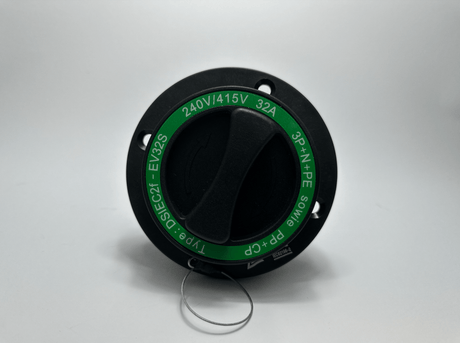 Een Type 2 Inlaat 16A/32A Knijpverbinding draaischakelaar in zwart met een groen 240V/415V 32A 3P+N+PE label is afgebeeld op een witte achtergrond. Een metalen ring aan de onderkant past op de 16A/32A aansluiting.