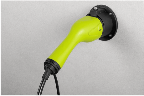 Een groene stekker voor het opladen van elektrische auto's is aangesloten op een zwart rond stopcontact tegen een lichtgrijze achtergrond, met de Kabelhouder type 2 laadkabel EV netjes ernaast.