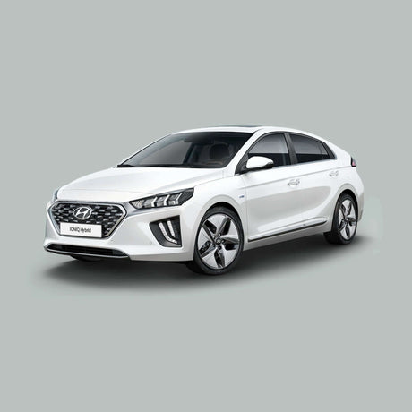 Een witte Hyundai Ioniq Hybrid staat geparkeerd op een effen, lichtgrijze achtergrond, gezien vanaf de linker voorkant. De auto heeft een modern design met strakke lijnen en zilverkleurige lichtmetalen velgen.