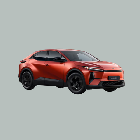 Een slanke, rode compacte SUV met zwarte wielen en getinte ramen, gefotografeerd onder een hoek op een effen lichtgrijze achtergrond. De auto heeft moderne, scherpe lijnen en een futuristisch ontwerp.