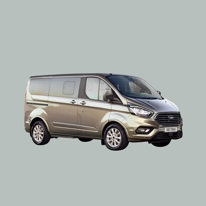 Een zilverkleurig Ford Transit busje staat geparkeerd op een effen, lichtgrijze achtergrond, gezien vanaf de linker voorkant. Het busje heeft getinte ramen en chromen details.