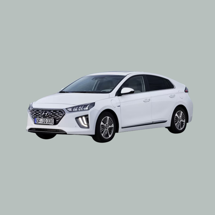 Een witte Hyundai Ioniq sedan staat geparkeerd op een effen, lichtgrijze achtergrond, gezien vanaf de linker voorkant. De auto heeft moderne LED-koplampen en een gestroomlijnd, aerodynamisch ontwerp.