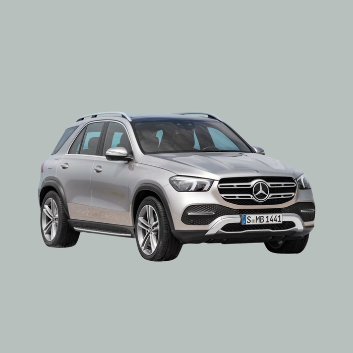 Een zilverkleurige Mercedes-Benz SUV is afgebeeld op een effen grijze achtergrond, gezien vanuit de hoek linksvoor. Het voertuig heeft moderne koplampen, een prominente grille, dakrails en lichtmetalen velgen.