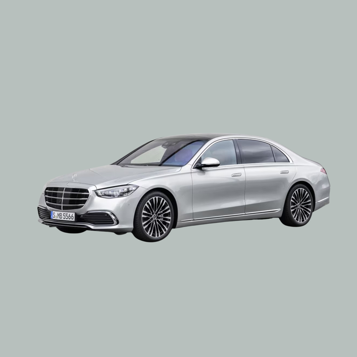 Een zilveren luxe sedan, waarschijnlijk een Mercedes-Benz, is afgebeeld onder een driekwart hoek op een effen grijze achtergrond. De auto heeft donker getinte ramen en meerspaaks lichtmetalen velgen.