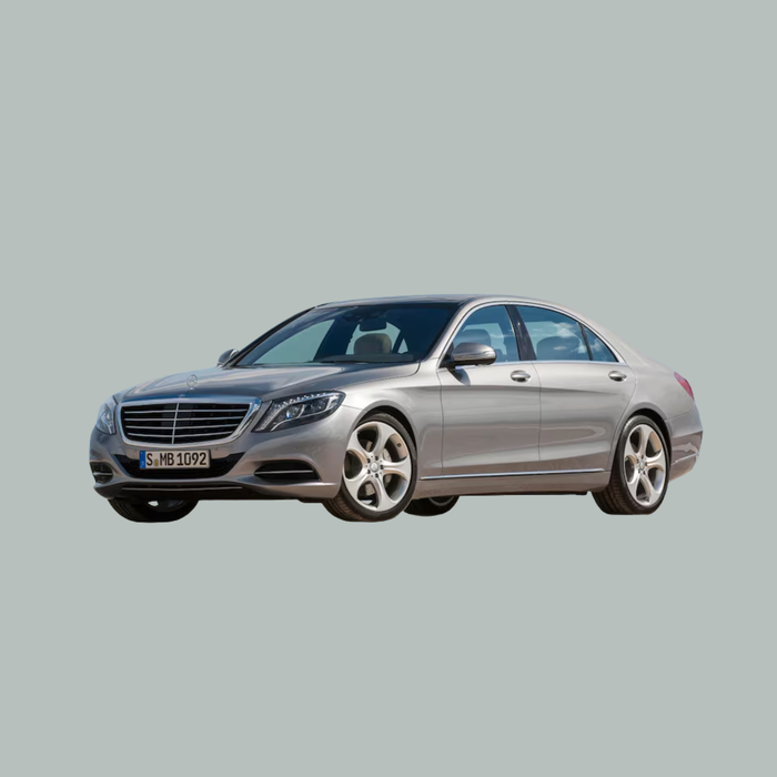 Een zilverkleurige Mercedes-Benz sedan staat geparkeerd op een effen, lichtgrijze achtergrond, gezien vanuit de hoek linksvoor.