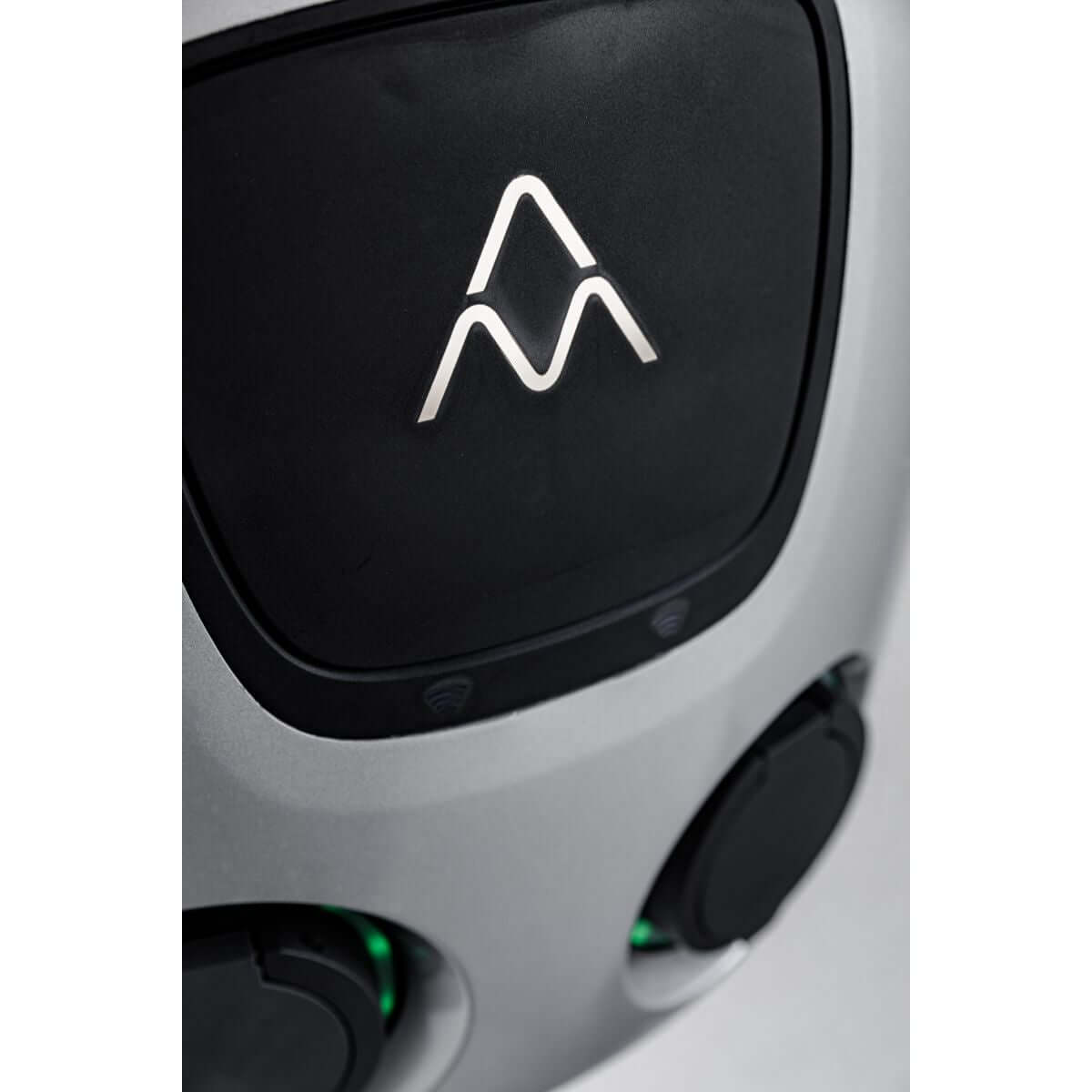 Close-up van de gestroomlijnde zwarte en zilverkleurige Laadstation Charge Amps Aura met Sim 2x22 kW 3-fase 32A bidirectioneel voertuig naar net, met afgeronde hoeken en twee ronde poorten met groene lampjes - ideaal voor elektrische auto's beladen.