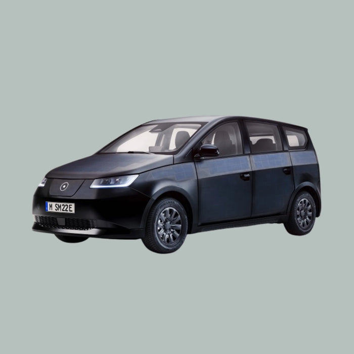 Een zwarte elektrische hatchback met zonnepanelen op de deuren en het dak, gefotografeerd op een effen lichtgrijze achtergrond.